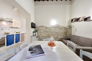 Una cocina moderna con armarios blancos, protector contra salpicaduras de piedra y un comedor con mesa, sillas y un libro.