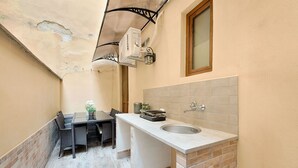 Una cucina compatta con lavello, un piccolo tavolo da pranzo con sedie e una ventola a soffitto.