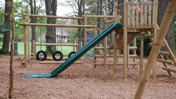 Explore the playground's natural surroundings and enjoy the slide, climbing elements, and platform.