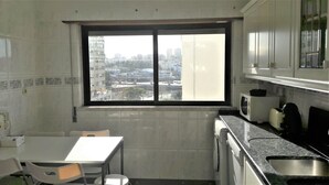 Una cocina pequeña con ventana, una mesa y electrodomésticos básicos.