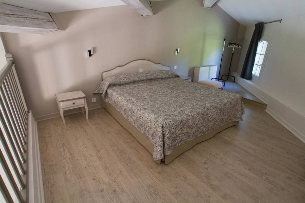 A bedroom with a bed, a nightstand, and a window.