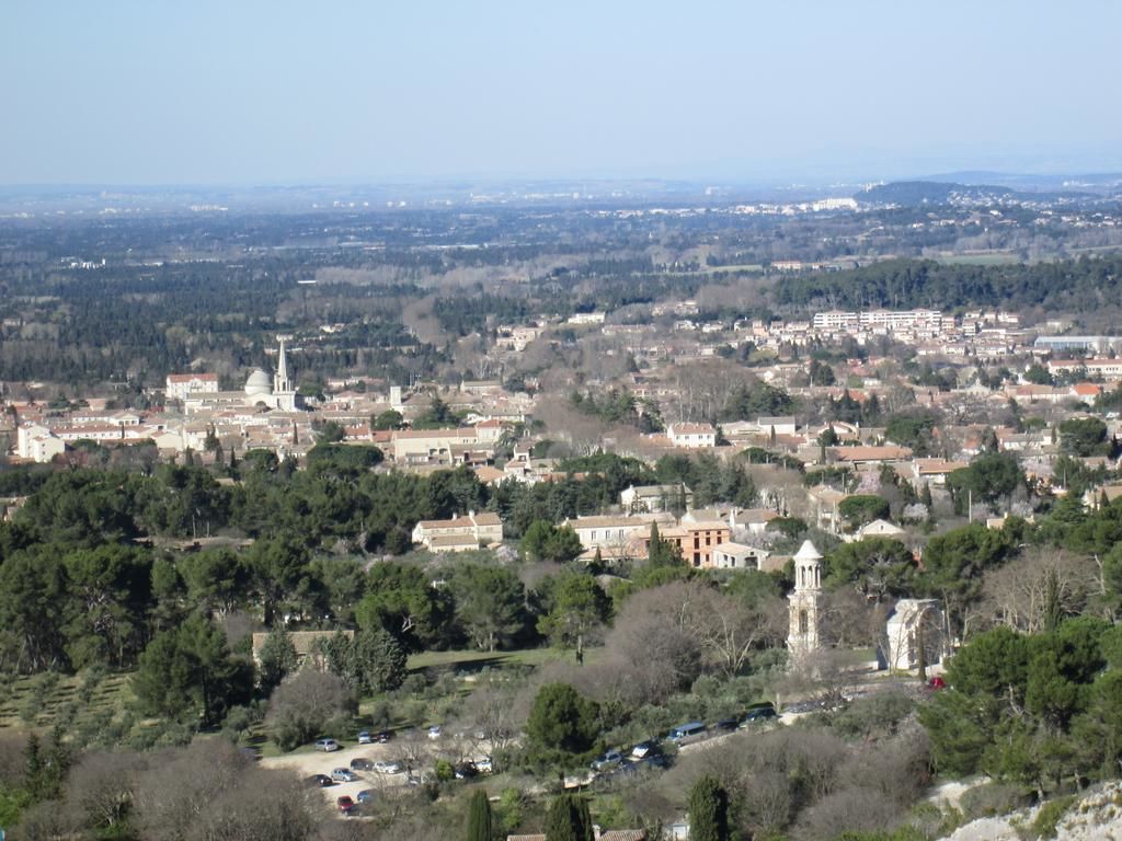 A panoramic view of a city with historic buildings, a prominent tower, and surrounding greenery.