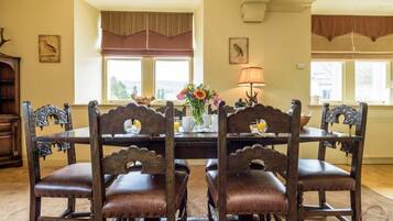 A dining area with a wooden table and chairs, a vase with flowers, and a lamp.