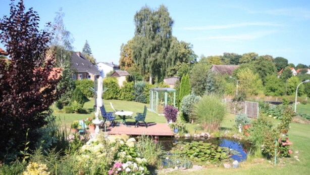 A garden with a pond, outdoor furniture, and a gazebo. - Vacation apartment in Strasen small - Holiday apartments directly on the Havel-Wasser (Wesenberg)