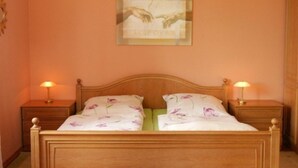 A bedroom with a wooden bed, two bedside tables with lamps, and a framed artwork on the wall. - Vacation apartment in Strasen small - Holiday apartments directly on the Havel-Wasser (Wesenberg)
