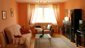 A living room with a sofa, armchair, and a television on a cabinet. - Vacation apartment in Strasen small - Holiday apartments directly on the Havel-Wasser (Wesenberg)