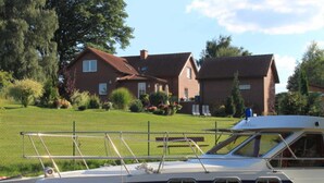 A boat docked near a house with a lawn and trees. - Vacation apartment in Strasen small - Holiday apartments directly on the Havel-Wasser (Wesenberg)