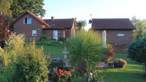 A two-story house with a brick exterior, a front yard with various plants and a small pond. - Vacation apartment in Strasen small - Holiday apartments directly on the Havel-Wasser (Wesenberg)