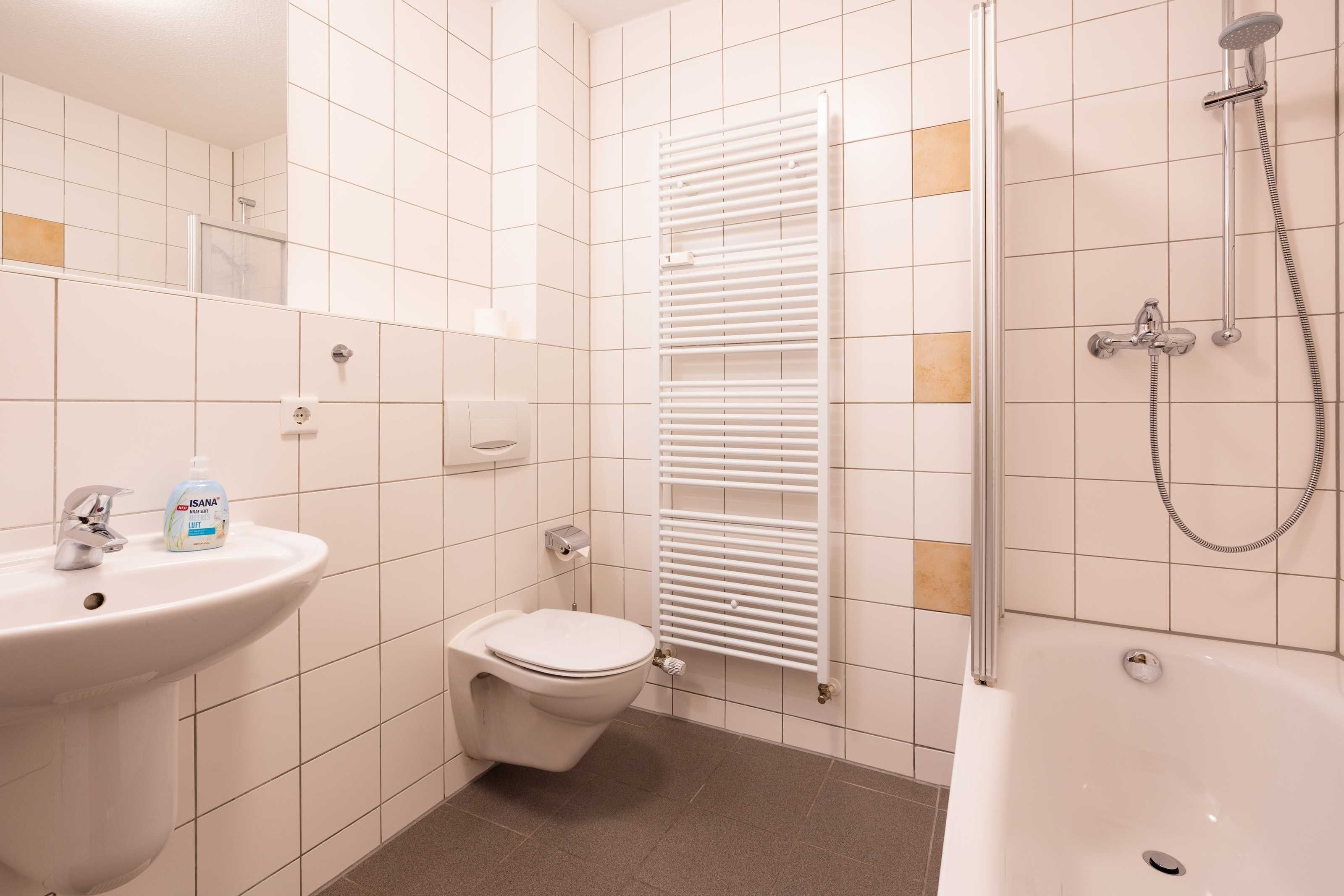 Et badeværelse med vask, toilet og badekar.