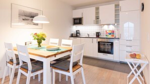 A modern kitchen with white cabinets, a microwave, and a coffee maker. - Sea breeze - Villa on the beach (new build) (Heringsdorf)