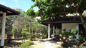 A covered outdoor area with a pergola, potted plants, and a pathway. - The Danish Villa (Arugam Bay)