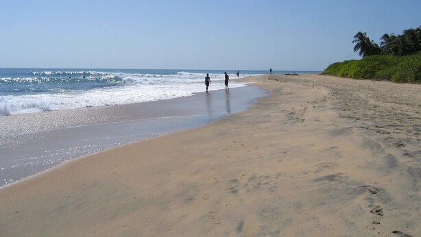 A wide sandy beach with gentle waves and a clear sky. - The Danish Villa (Arugam Bay)