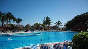 Une piscine avec des chaises longues et des palmiers.