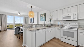 Eine moderne Küche mit weißen Schränken, einer Arbeitsplatte aus Granit, einer eingebauten Mikrowelle und einem Backofen.
