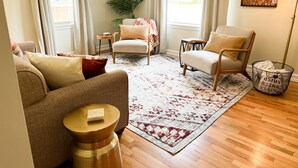 Un salon avec deux canapés, une table basse, une table d’appoint, une plante en pot et un tapis.