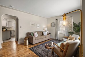 A modern living room with a sofa, armchair, and a unique light fixture. - Mi-Fall Getaway Near Lake Michigan Dog Friendly + Spacious Fenced Yard (Muskegon)