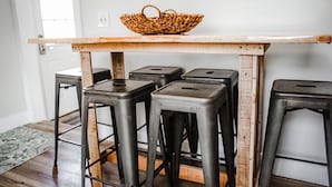 Un espace bar avec une table en bois et quatre tabourets en métal.