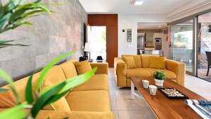 Ein modernes Wohnzimmer mit zwei senfgelben Sofas, einem Holztisch und einer Topfpflanze.