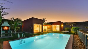 Ein modernes Haus mit Swimmingpool, Terrasse und Blick auf die umliegende Landschaft.