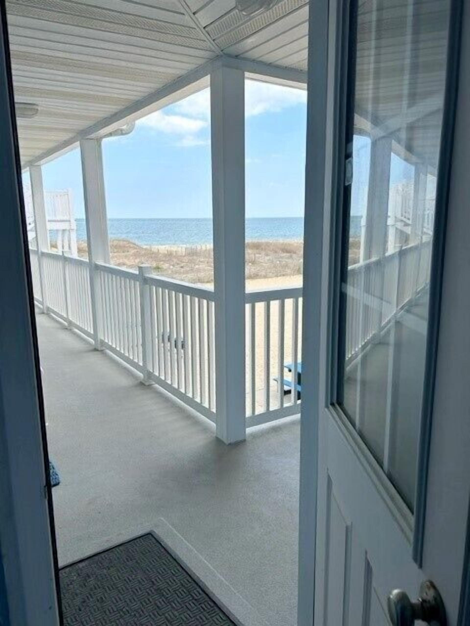 A covered porch with a view of the beach and ocean.
