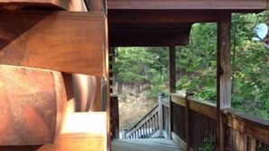 Une terrasse en bois mène à un espace abrité d’où l’on peut admirer un paysage boisé.