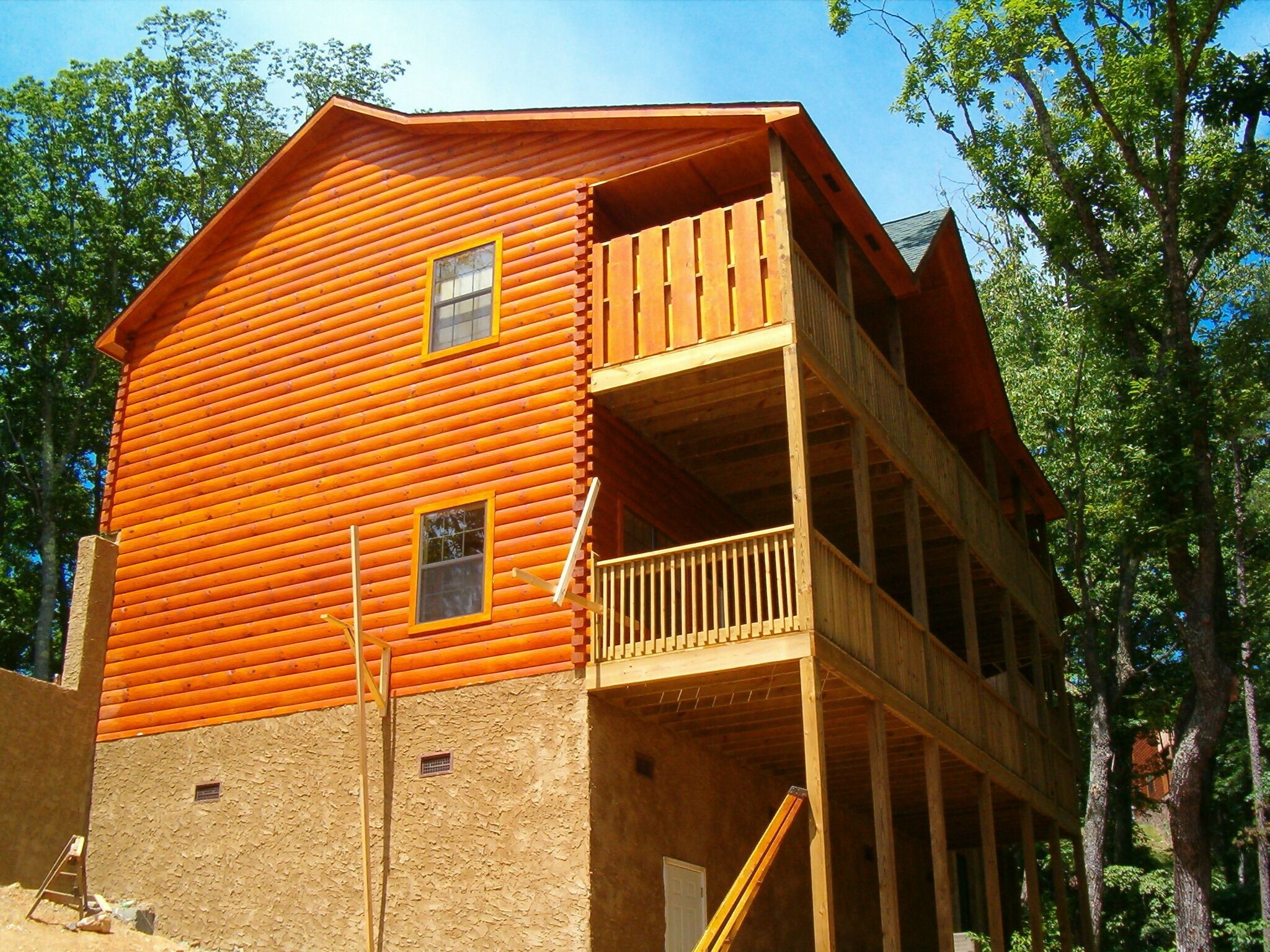 A two-story log cabin with a balcony on the upper floor.