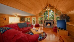 L’intérieur d’un chalet confortable, avec un canapé rouge, une table basse en bois et une cheminée.