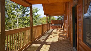 Une terrasse en bois offrant une vue sur les arbres et les montagnes.