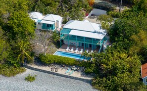A resort with a pool, multiple guest rooms, and a lush surrounding. - Sunset Beach: Beachfront Villa! Pool! Hot Tub! (St. John)