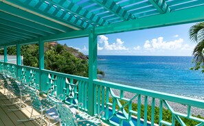 A covered outdoor seating area with chairs and a view of the ocean. - Sunset Beach: Beachfront Villa! Pool! Hot Tub! (St. John)