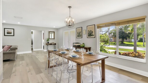 A dining area with a long wooden table, clear chairs, and a chandelier. - WatersEdge: Lakefront Fishing-Saltwater Pool-GameRoom (Weston)