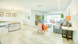 A spacious living area with a dining table, a sofa, and a TV. - WatersEdge: Lakefront Fishing-Saltwater Pool-GameRoom (Weston)