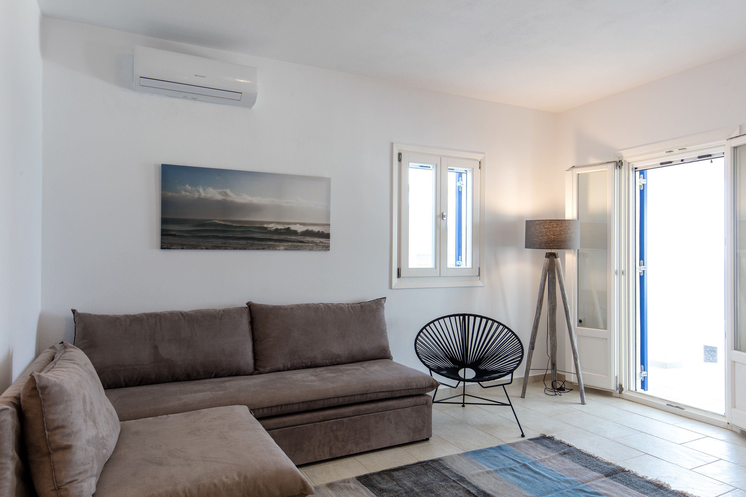 A living room with a sofa, a chair, a painting, and a lamp.