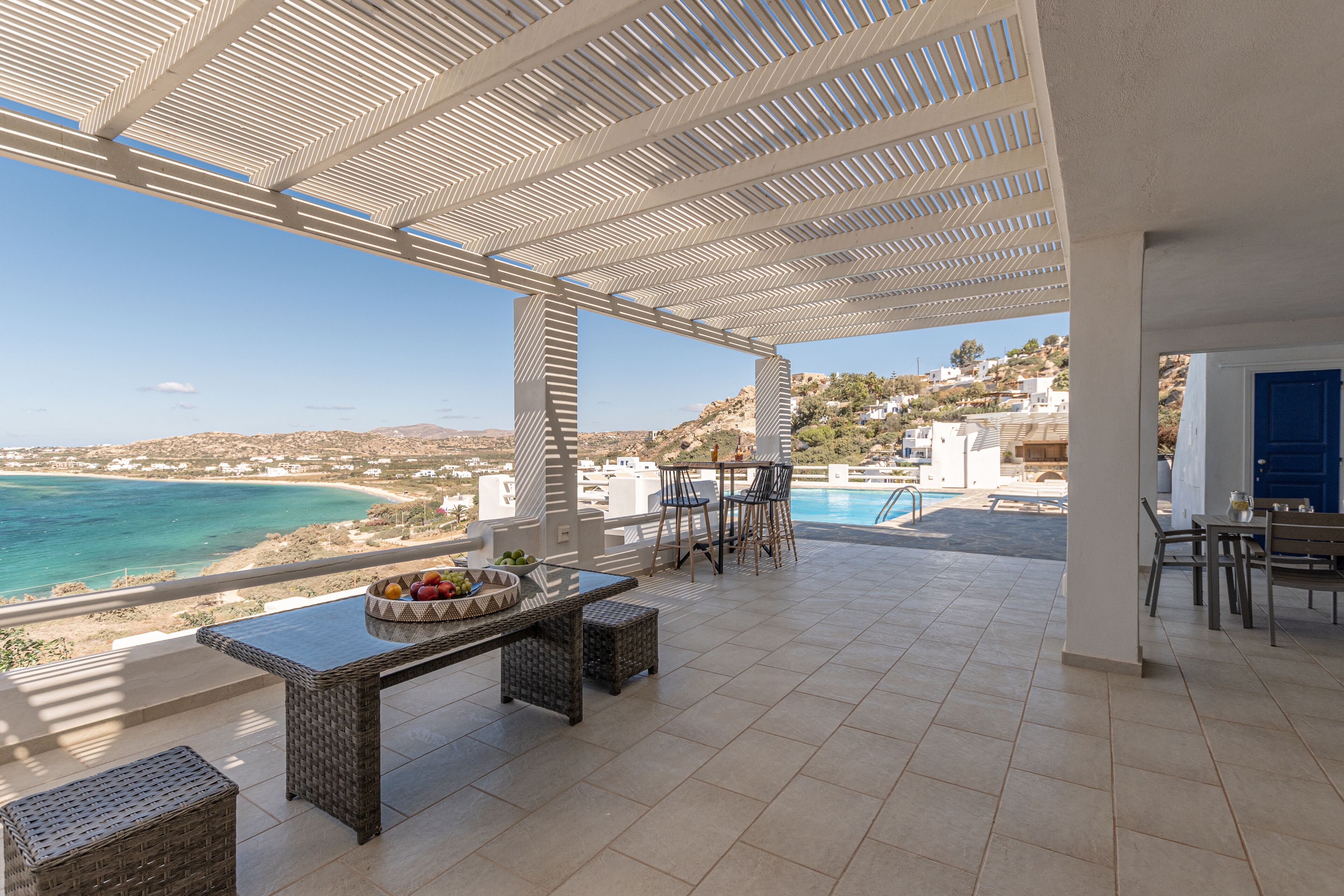 Una terraza con piscina, mobiliario exterior y vista al mar.