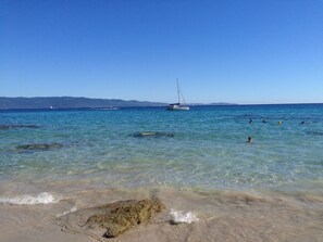 A beach with clear water, a sailboat, and people swimming. - Magnificent sea view More than 50 star reviews from my hosts !!! (Ajaccio)