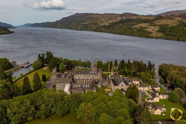 A large estate with a castle-like building, a river, and surrounding greenery.
