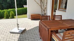 A wooden patio table with chairs, a small wooden stool, and a metal chair with a backrest. - Apartment Betula, near Pullman City in the district of Passau in the Bavarian Forest (Fürstenstein)