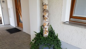 A white exterior wall with a wooden sign spelling "BEREKA" and a potted plant with green foliage. - Apartment Betula, near Pullman City in the district of Passau in the Bavarian Forest (Fürstenstein)