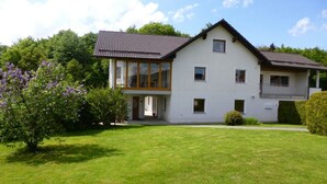 A two-story house with a large front lawn and a balcony. - Apartment Betula, near Pullman City in the district of Passau in the Bavarian Forest (Fürstenstein)