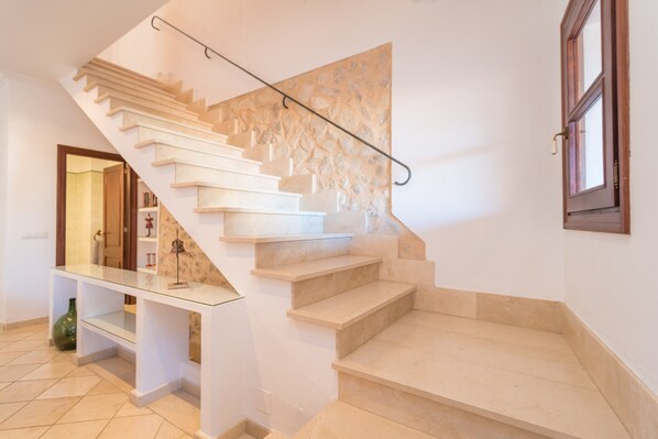 Un escalier moderne avec une étagère en verre et un mur en pierre.