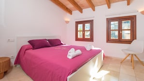 A bedroom with a bed, pillows, a chair, and a window.
