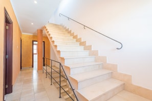 Un escalier doté d’une rampe métallique, menant à un palier où se trouve une porte.