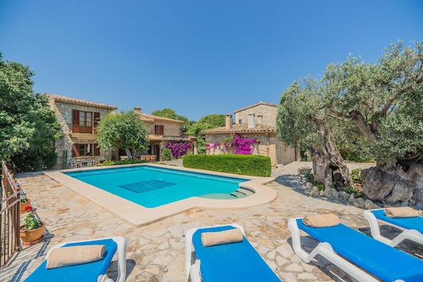 A poolside area with stone flooring, blue lounge chairs, and a clear blue pool. - Mastaguera Mallorcan style villa with pool and spectacular views (Pollença)