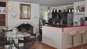 A modern kitchen with a central island, bar stools, and a fireplace. - villa near cannes (Mougins)