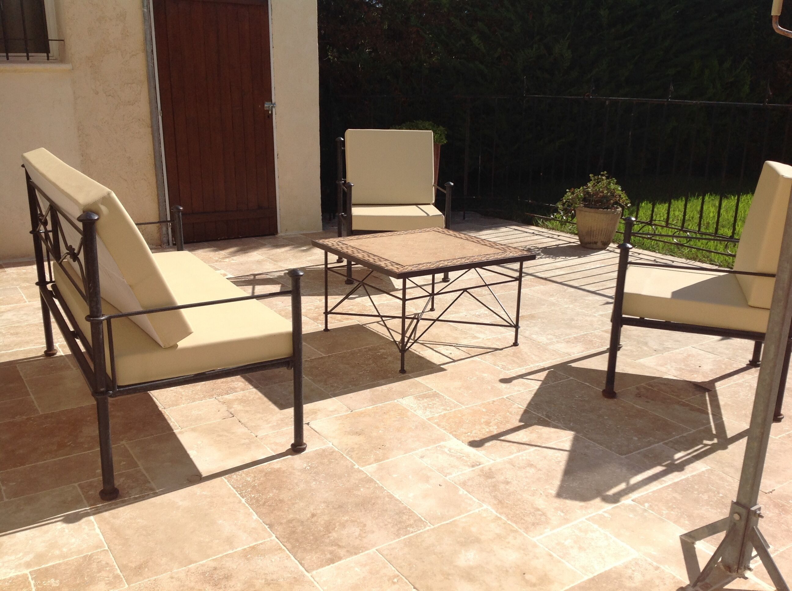 An outdoor patio with a metal table and four chairs.