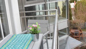 A balcony with a table, chairs, and a potted plant.