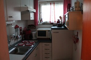 Cocina compacta con microondas, estufa, lavaplatos y armarios.