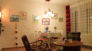 A dining area with a table, chairs, and a hanging light fixture. - Apartment seal (Wangerland)