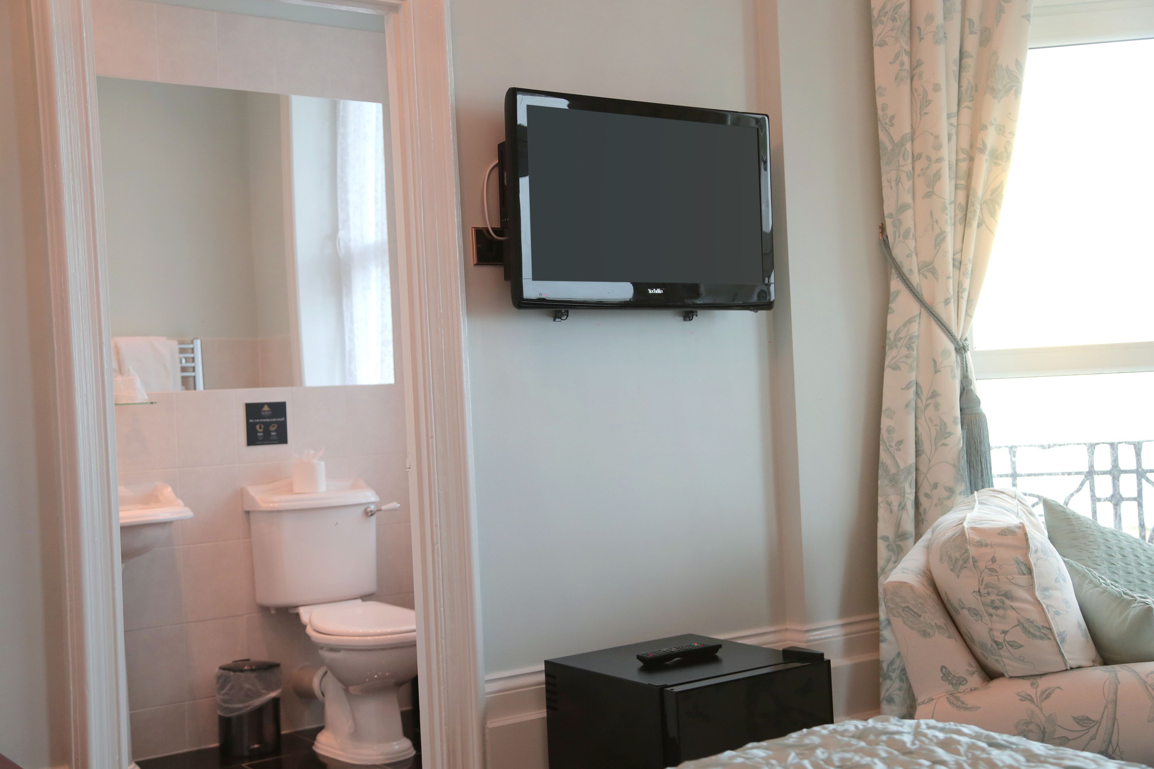 A modern bathroom with a toilet, sink, and a mounted TV.
