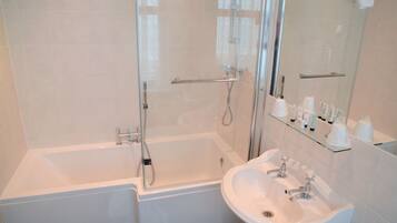Un baño moderno con ducha de vidrio, una bañera blanca y un lavamanos de dos grifos.